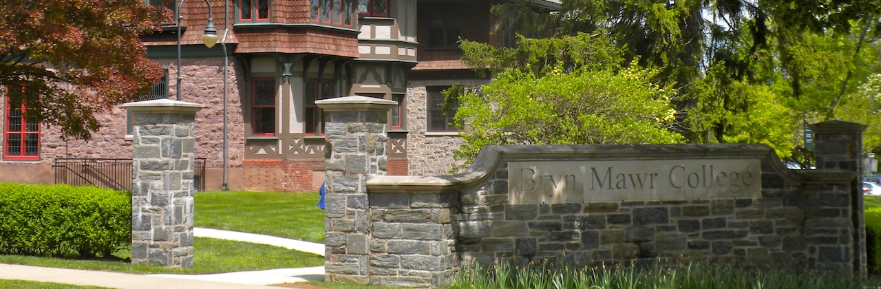 Stone sign reading "Bryn Mawr College" in front of a three-story house