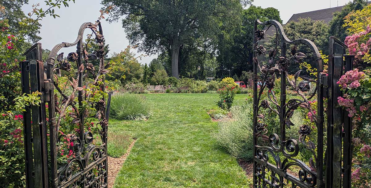 Metal gates leading to a well-tended garden